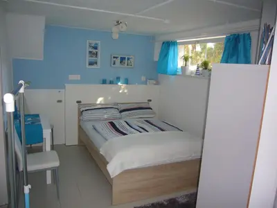 a small bedroom with a bed with blue walls at Reni's Oase am Bodensee in Kesswil