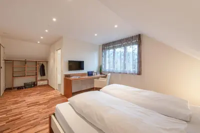 a bedroom with a white bed and a desk at Hotel Rössli in Zuzwil