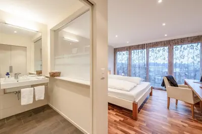 a bedroom with a bed and a sink and a mirror at Hotel Rössli in Zuzwil