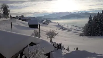 a snow covered mountain with the sun in the background at Schwellbrunn,Ferienwohnung mit Säntissicht in Schwellbrunn