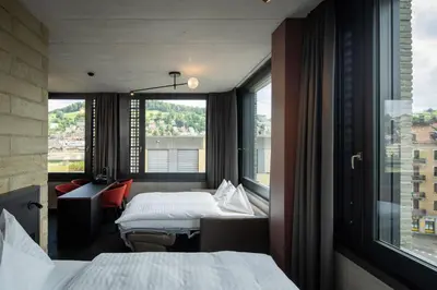 a hotel room with two beds and a window at Tailormade Hotel LEO St Gallen in St. Gallen