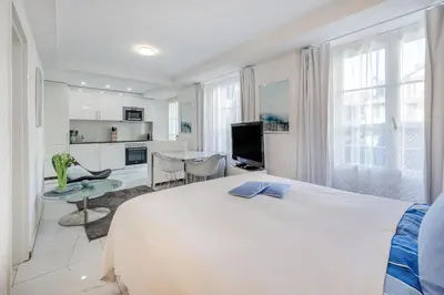 a white bedroom with a black chair and a bed at Aparthotel Mama Home Stankt Georgen in St. Gallen
