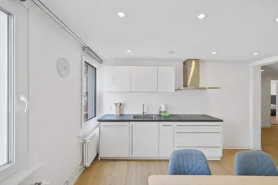 a kitchen with white cabinets and blue chairs at book2stay - Apartments Herisau in Herisau
