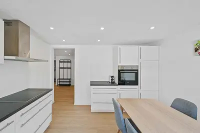 a kitchen with white cabinets and a wooden table at book2stay - Apartments Herisau in Herisau
