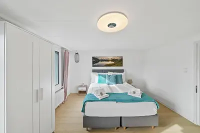 a white bedroom with a bed with blue accents at book2stay - Apartments Herisau in Herisau