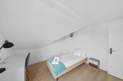 a small bedroom with a bed in a white room at book2stay - Apartments Herisau in Herisau