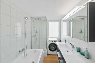 a bathroom with two sinks and a shower and a washing machine at book2stay - Apartments Herisau in Herisau