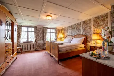 a bedroom with a bed and a desk and windows at Schloessli Herrenhof in Herrenhof