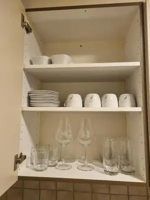 a cupboard with wine glasses and bowls and plates at 24-7 Rooms in Sennwald