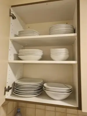 a cabinet filled with white plates and bowls at 24-7 Rooms in Sennwald