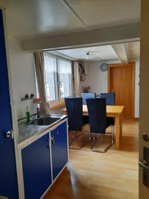 a kitchen and dining room with a table and blue chairs at Vreni`s Ferienwohnung in Gais