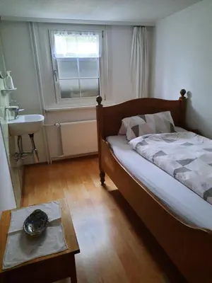 a bedroom with a bed and a sink and a table at Vreni`s Ferienwohnung in Gais