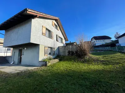 a white house on a green yard with a fence at Blässchopfhüsli in Nesslau