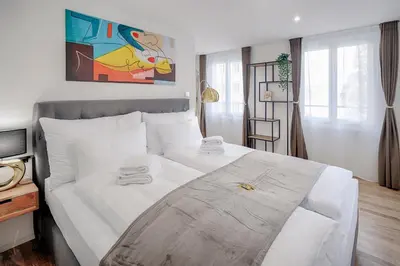 a bedroom with a large bed with white sheets at VISIMO Apartments St Georgen-Strasse St Gallen - Design City Nature in St. Gallen