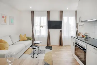 a white living room with a couch and a kitchen at VISIMO Apartments St Georgen-Strasse St Gallen - Design City Nature in St. Gallen