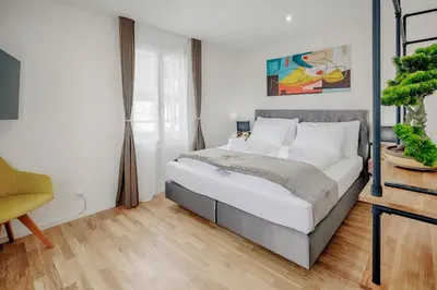 a bedroom with a large bed and a yellow chair at VISIMO Apartments St Georgen-Strasse St Gallen - Design City Nature in St. Gallen
