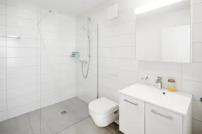 a white bathroom with a shower and a toilet at VISIMO Apartments St Georgen-Strasse St Gallen - Design City Nature in St. Gallen