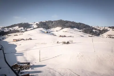 a snow covered slope with houses on a mountain at Appenzeller Huus Löwen in Gonten