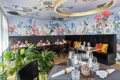 a restaurant with tables and chairs and floral wallpaper at Appenzeller Huus Löwen in Gonten
