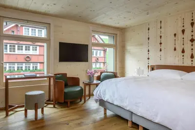 a bedroom with a bed and a desk and a tv at Appenzeller Huus Löwen in Gonten