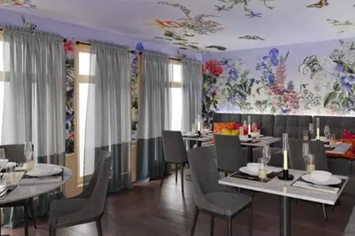 a dining room with tables and chairs and flowers on the walls at Appenzeller Huus Löwen in Gonten