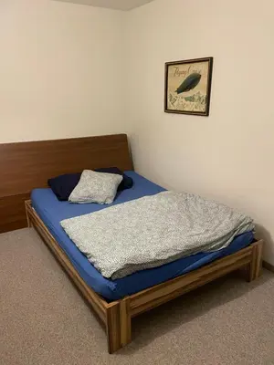 a bed with a blue mattress and a picture on the wall at Central Room with amazing view in St. Gallen