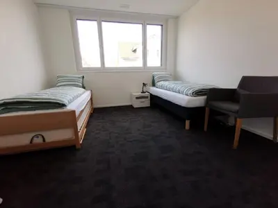 a room with two beds and a chair and a window at Ferienwohnung Hirschen in Gossau