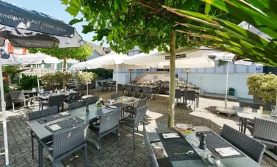 an outdoor restaurant with tables and chairs and umbrellas at Landgasthof Adler in 9304 Bernhardzell in Häggenschwil