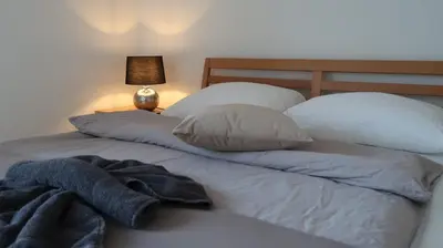 a bed with white sheets and pillows and a lamp at MBar in Altnau