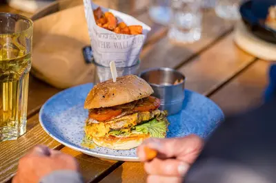 a blue plate with a sandwich and fries on a table at Hotel Restaurant Berghaus Malbun Buchserberg in Buchs