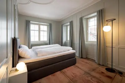 a bedroom with a bed and two windows at JACOB 1808. fine historic town apartments in Bischofszell