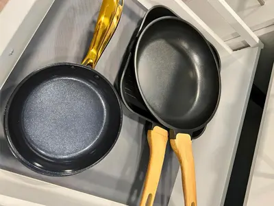 two black pans and wooden utensils in a drawer at Ferienhausträume Oase Bodensee in Kreuzlingen